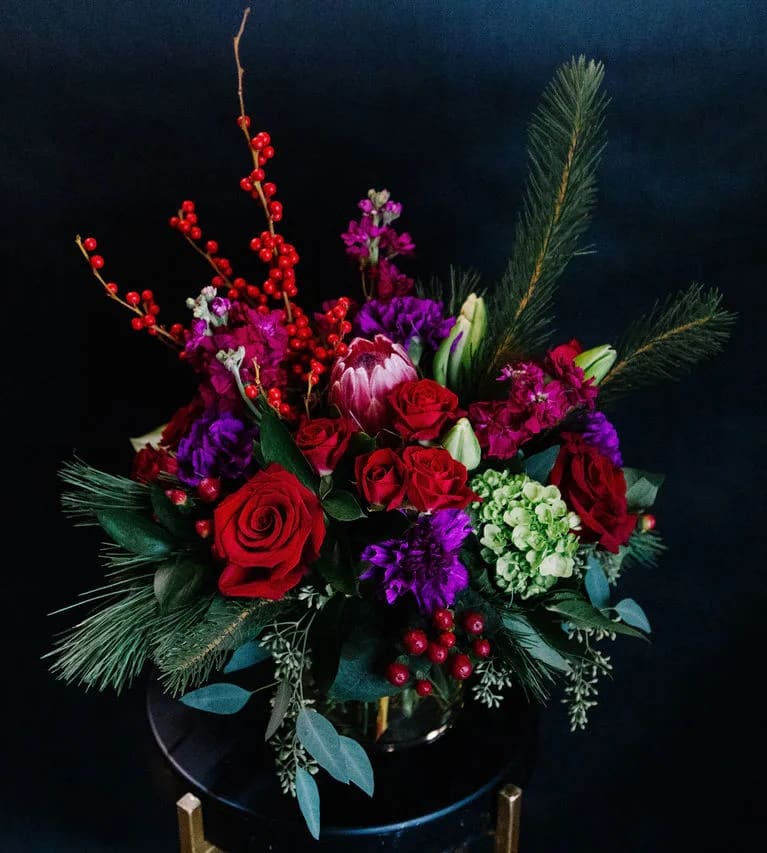 Holiday Jewel - A rich mix of jewel toned blooms designed in a modern low cylinder, accented with eucalyptus and winter pines.