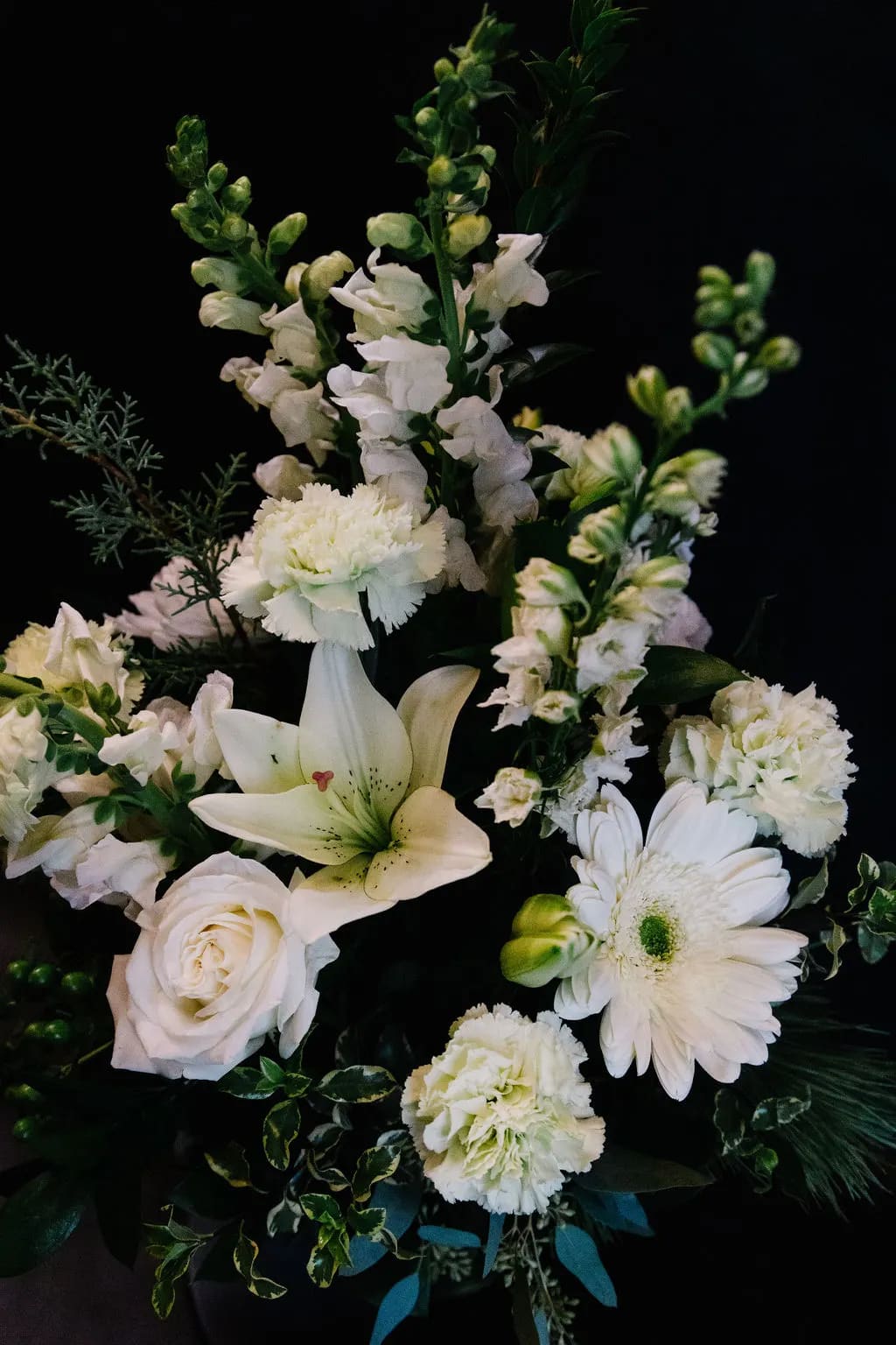 December Blooms - A traditional mix of green and white blooms designed in an 8&quot; tall gathering  vase.