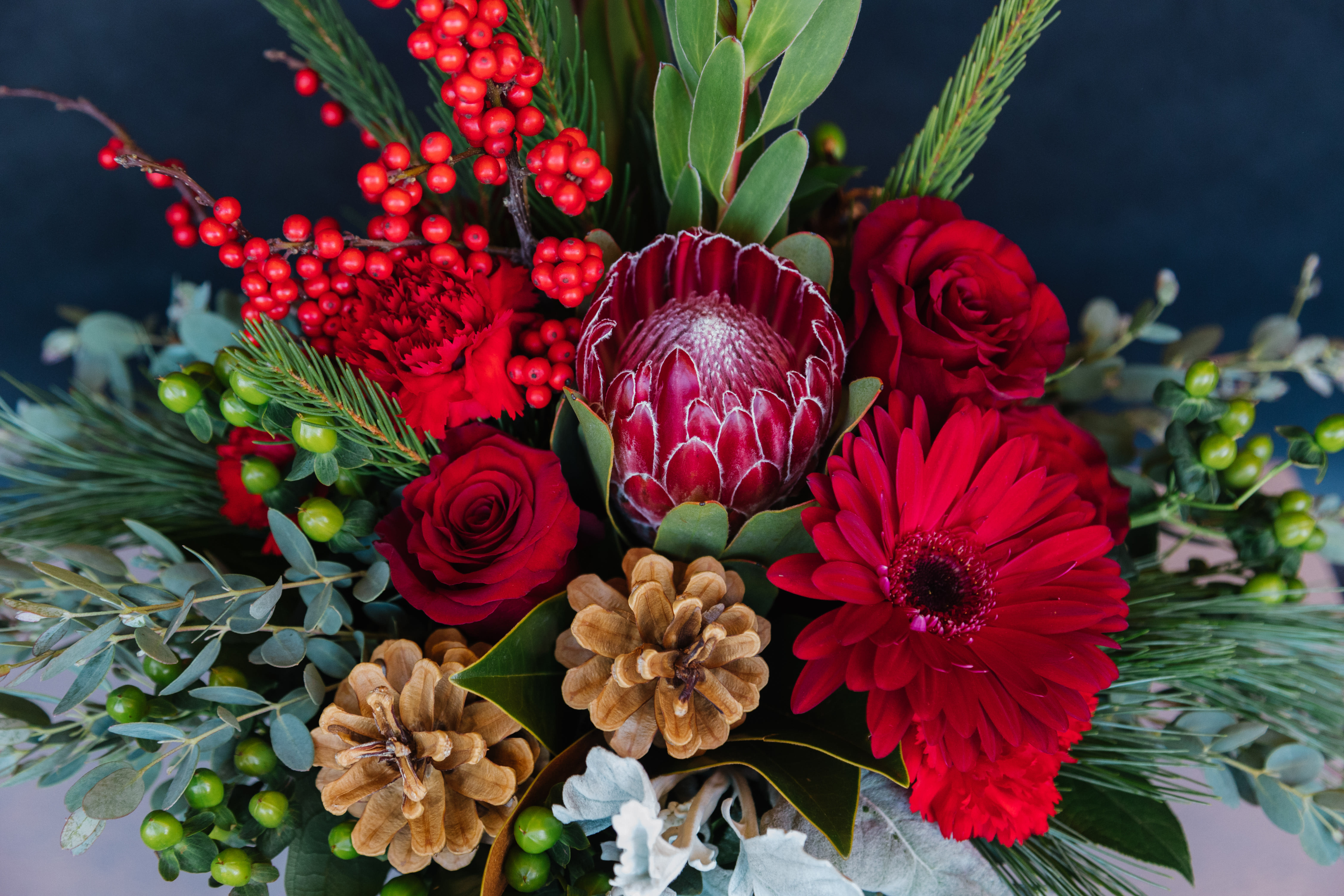 Designer's Choice Holiday Centerpiece - Designer's choice holiday centerpiece with an assortment of winter pines, cones, berries and a mix of Christmas flowers.