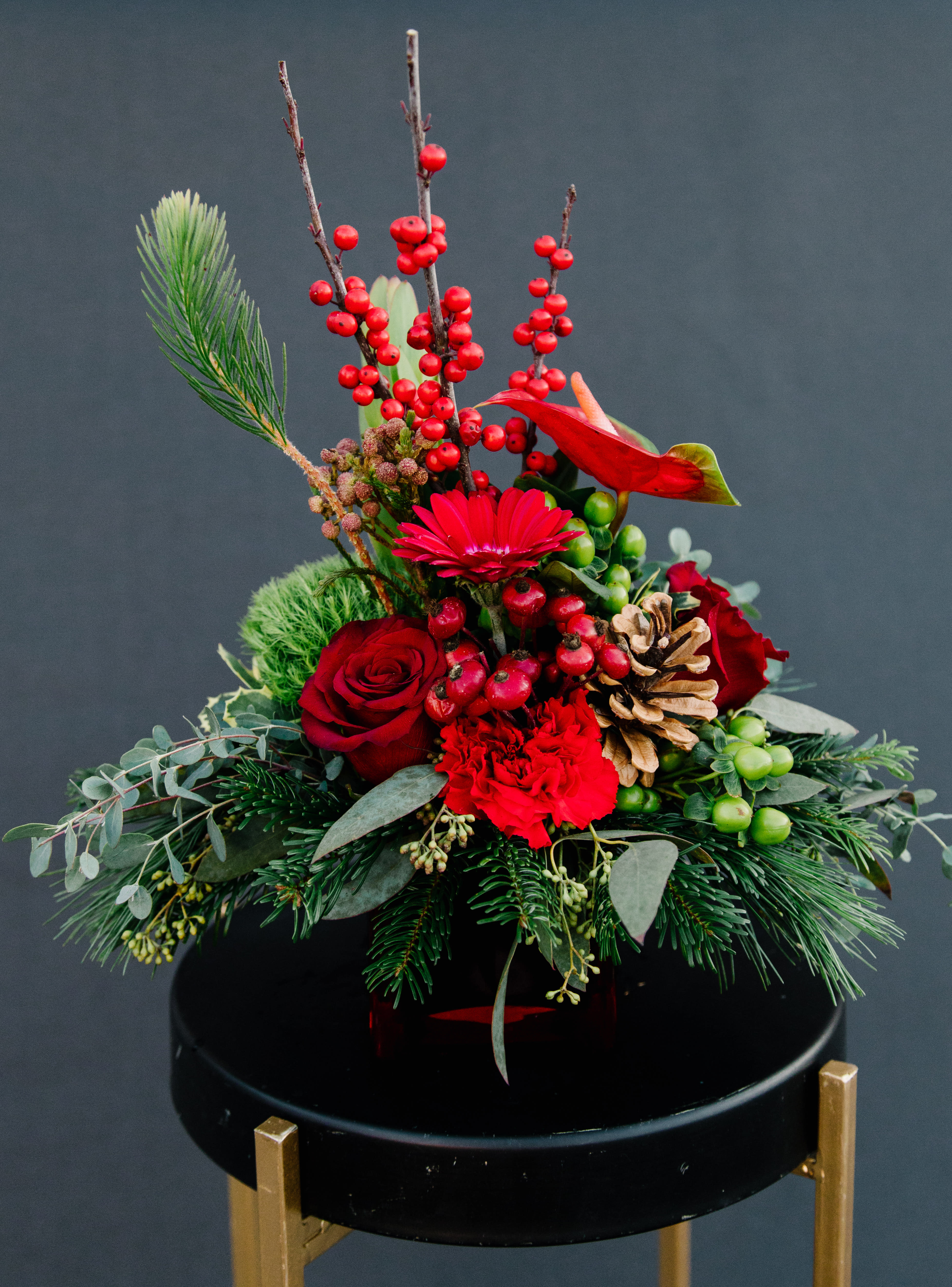 Merry &amp; Bright - A bright sampling of merry holiday blooms, pinecones &amp; berries including roses, carnations, mini gerbera and fragrant pine designed in a 4x4 ruby red cube.