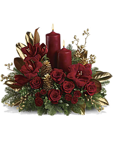 Season Greeting Centerpiece - A striking seasonal statement for the dining table, hallway or entryway, this gorgeous arrangement is a festive mix of reds, golds and greens with two dramatic pillar candles for a warm glow. Luxurious red amaryllis and red roses are contrasted with fragrant noble fir and golden, glittering pinecones, magnolia leaves and berries.