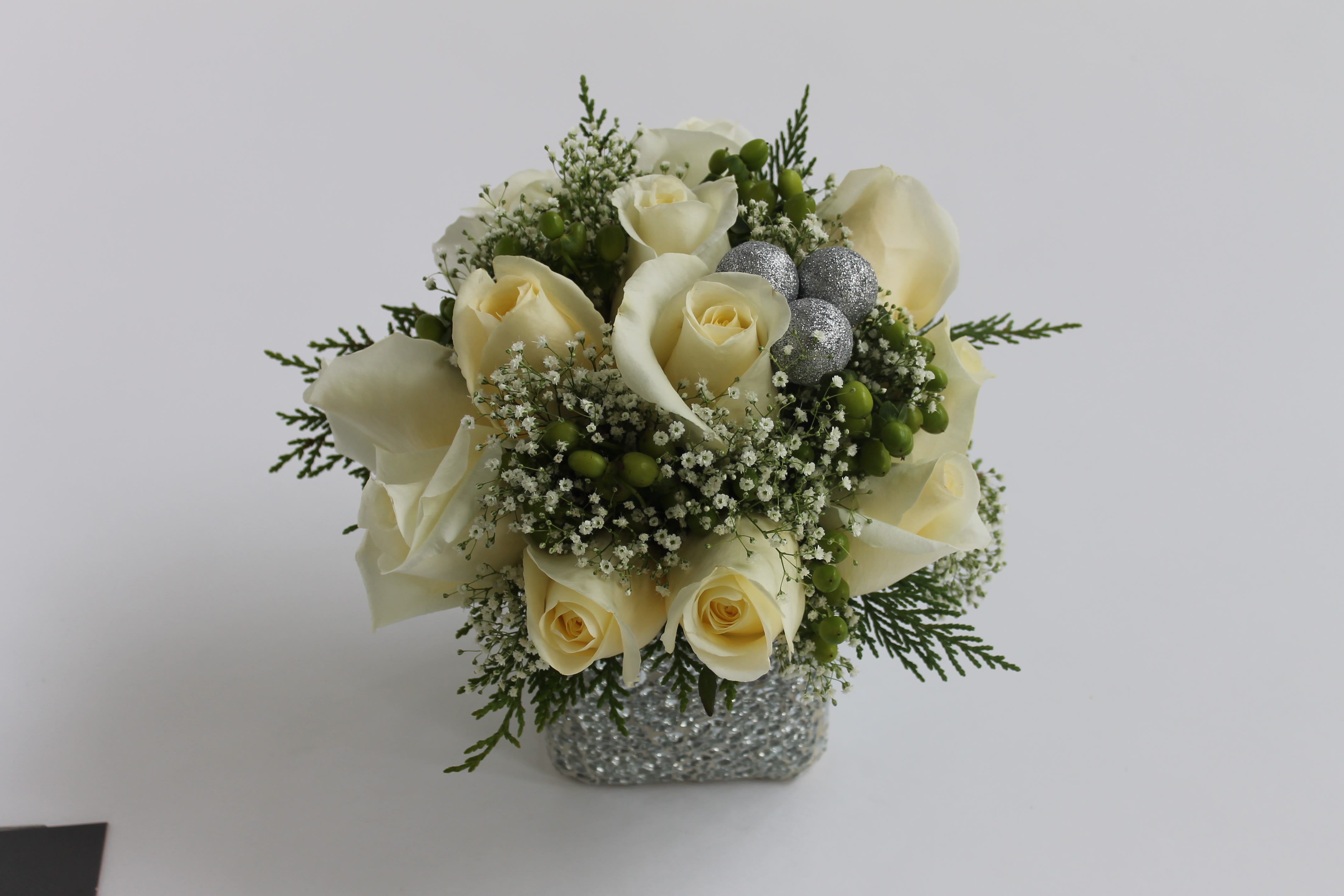 Snow White Bouquet - Celebrate the season with this wintery mix of white roses, snowflake gypsophlia, hypericum berries and Christmas cedar, accented with frosted holiday ornaments. Add an elegant crackled-mirrored glass mosaic vase for a Christmas centerpiece from the heart.