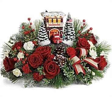 Thomas Kinkade's Festive Fire Station Bouquet - celebrating our first responders with a vintage styled hand-painted light-up Thomas Kinkade sculpture. We fill it with beautiful seasonal flowers and evergreens. A true collectors item.