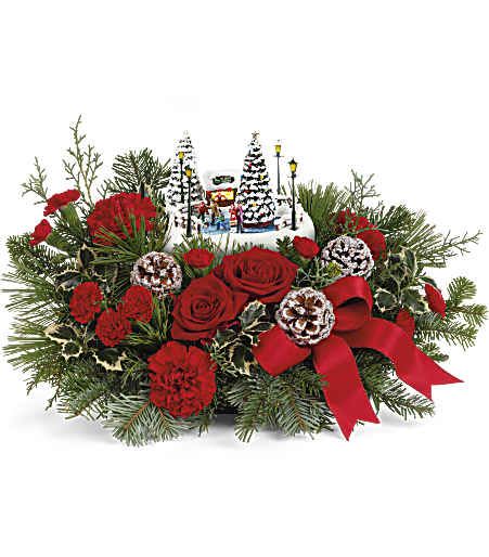 Thomas Kinkade's Oh What Fun  Bouquet - Celebrate the season with this delightful Thomas Kinkade collectible, nestled among festive red roses and winter greens-a memorable gift that lights up with a classic ice skating scene for extra holiday joy.  Celebrate the holidays with Thomas Kinkade's Oh What Fun arrangement. It includes vibrant red roses, classic red carnations, and miniature red carnations, accented with variegated holly, noble fir, white pine, and cedar. Delivered in Teleflora's charming Thomas Kinkade's Oh What Fun Keepsake, it makes a festive seasonal centerpiece. Approximately 19 1/2&quot; W x 10 3/4&quot; H