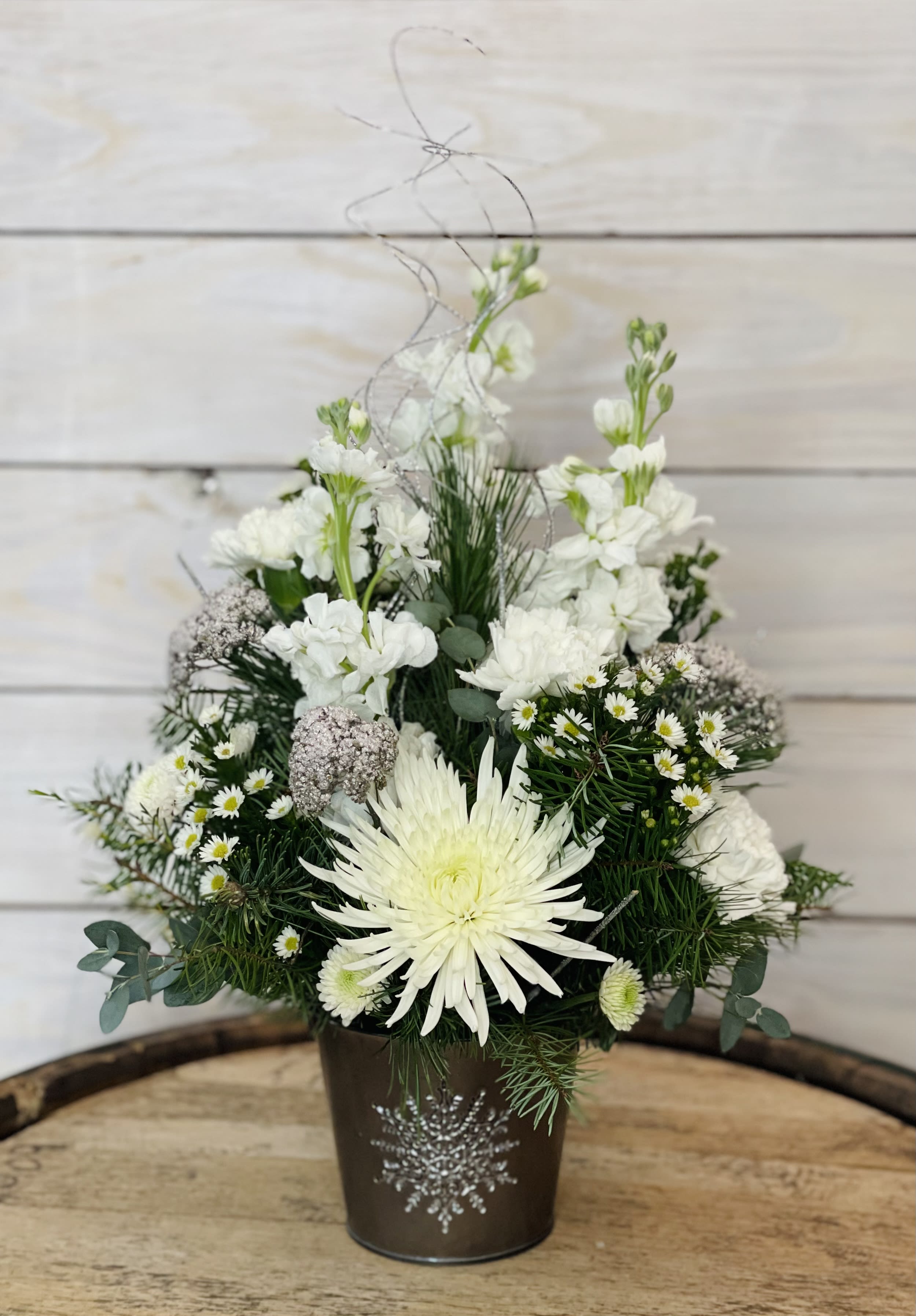 Silver Snowflake - White flowers and winter greenery fill this silver and sparkle snowflake bucket. Feel fun and classy with this winter arrangement. ****We will try our best to match the flowers in the picture, but there may be times when we substitute flowers. We will always try to make it have the same look and feel as the original.****