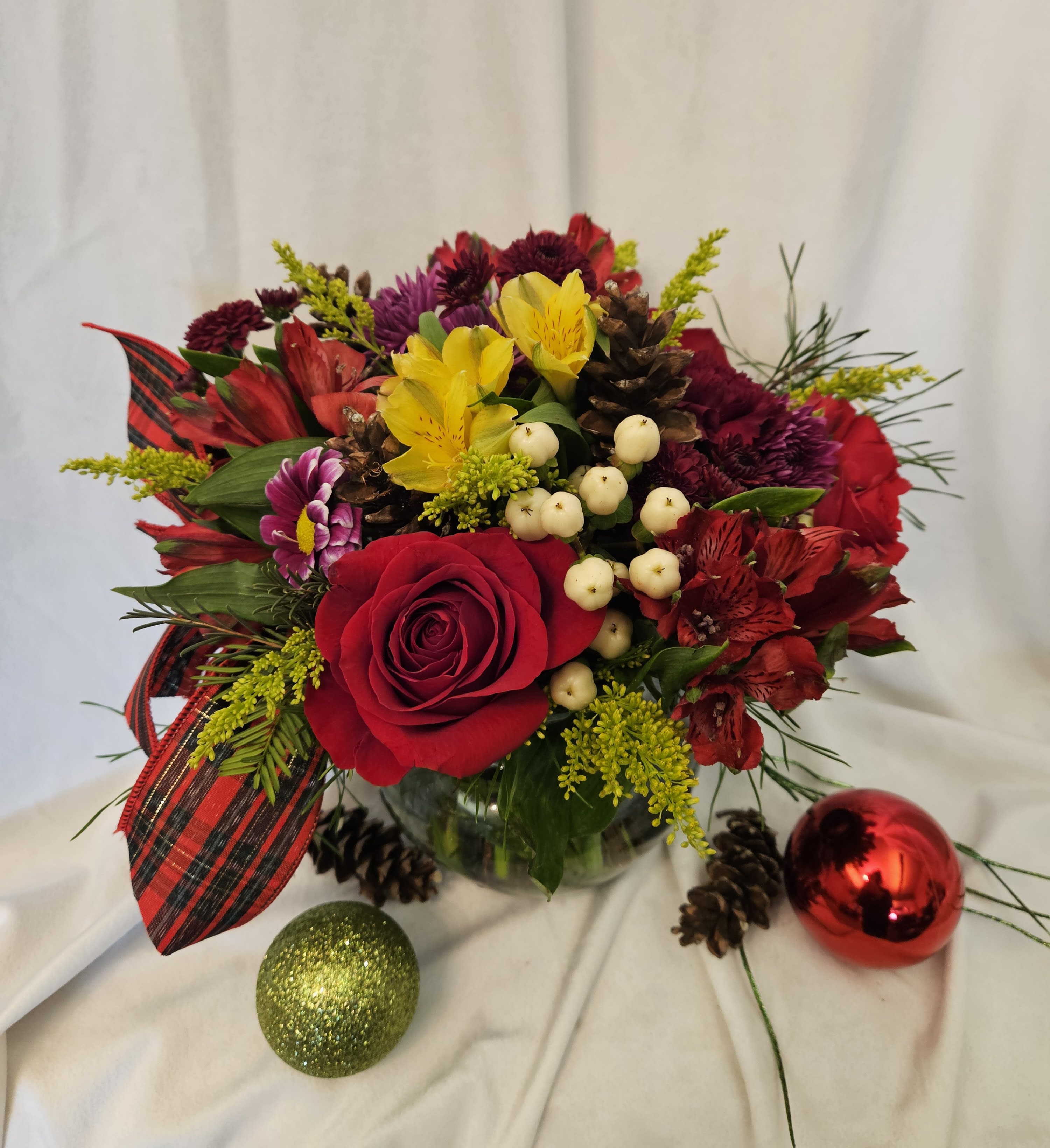 Merry and Bright - Vibrant vase arrangement with lush holiday greenery, red roses, alstroemeria, pon poms, carnations, and pine cones.