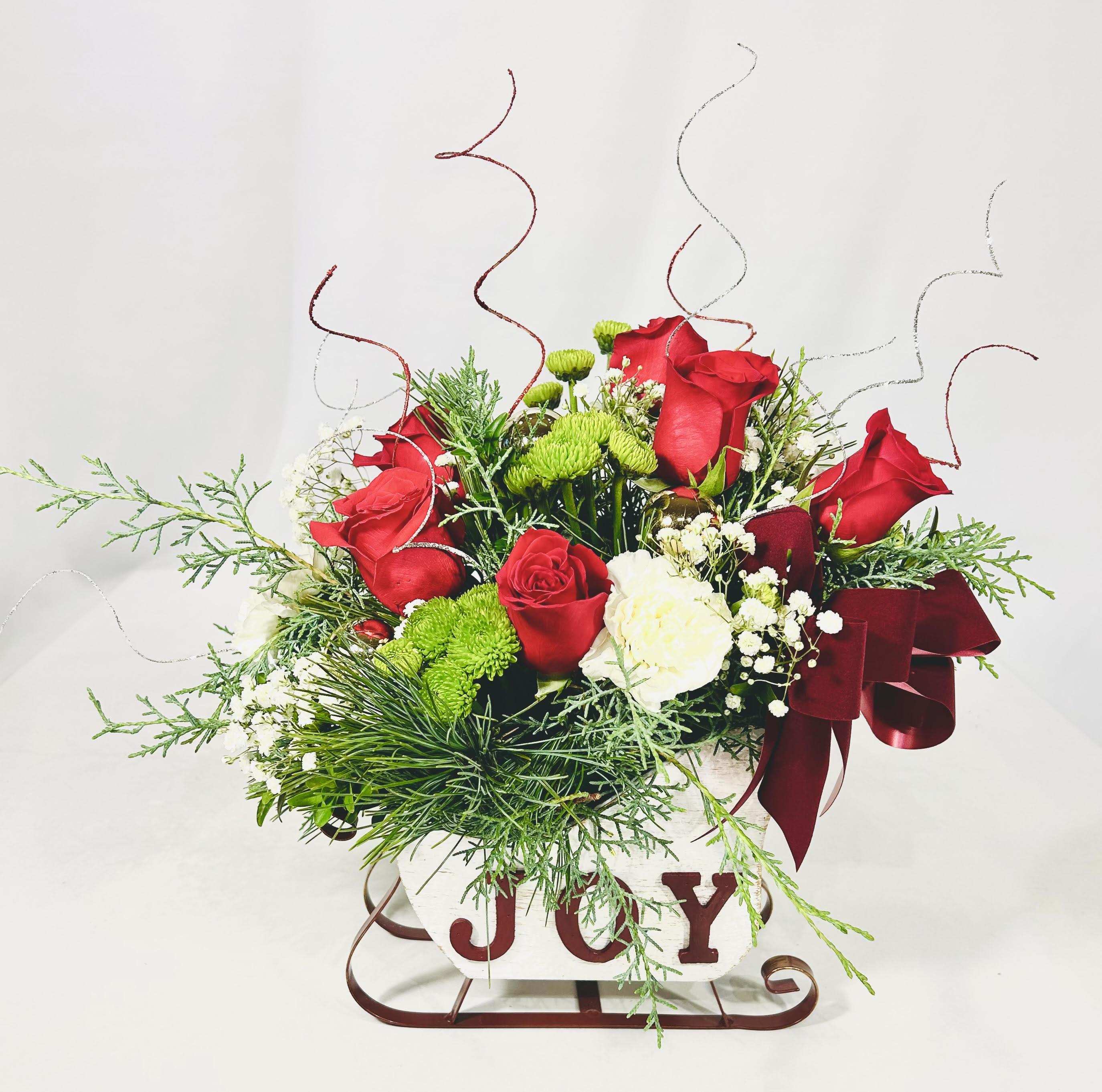 Joy to the World Christmas Sleigh - Christmas Wooden White Sleigh with JOY in red lettering. If you love an arrangement that can be a centerpiece, sit on the end table or brighten someone's day this Christmas this is it! Christmas greenery, white carnations, red roses, and green buttons with ting. 12" H  9" L 