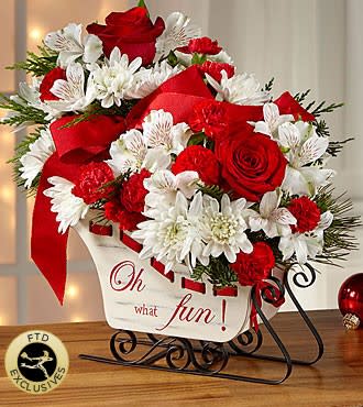 FTD Holiday Traditions Bouquet - A rustic sleigh accompanies this cheery keepsake bouquet! Make you loved one's holiday &quot;merry and bright&quot; by sending these beautiful blooms! The sled container may vary in color but it will be in a sled container. The flowers may vary as we use what looks the best at the time ordered.