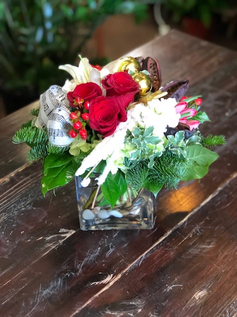 Christmas Carols - A European style bouquet with Christmas greens, red roses, hydrangea and ribbon accents.