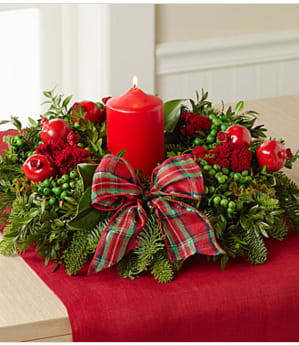 Hearts Aglow Holiday Centerpiece - The Hearts Aglow Holiday Centerpiece brings gorgeous color and light to the holiday table with its rich blooms and lush fragrant greens. A 5-inch red pillar candle candle smay be tapers is beautifully surrounded by an arrangement of fresh magnolia leaves and flat cedar with golden tips. Perfectly accented with frosted apples and red flax berries, this centerpiece will make a wonderful gift for friends and family or an incredible way to add to the festive beauty of your own home. the ornament may vary. Candle included . Centerpiece is 13-inches in diameter. Your purchase includes a complimentary personalized gift message.