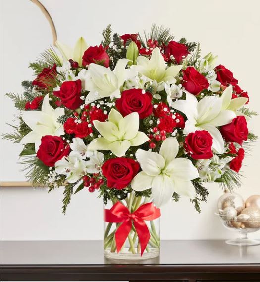 Fields of Europe Christmas LUXE - Our best-selling Christmas bouquet, in a newly designed luxury styling. This generous gathering of red and white blooms is accented by lush greenery all around. Designed in a classic glass vase finished with a red bow, our abundant arrangement captures the festive beauty of the holiday season with every elegant detail.