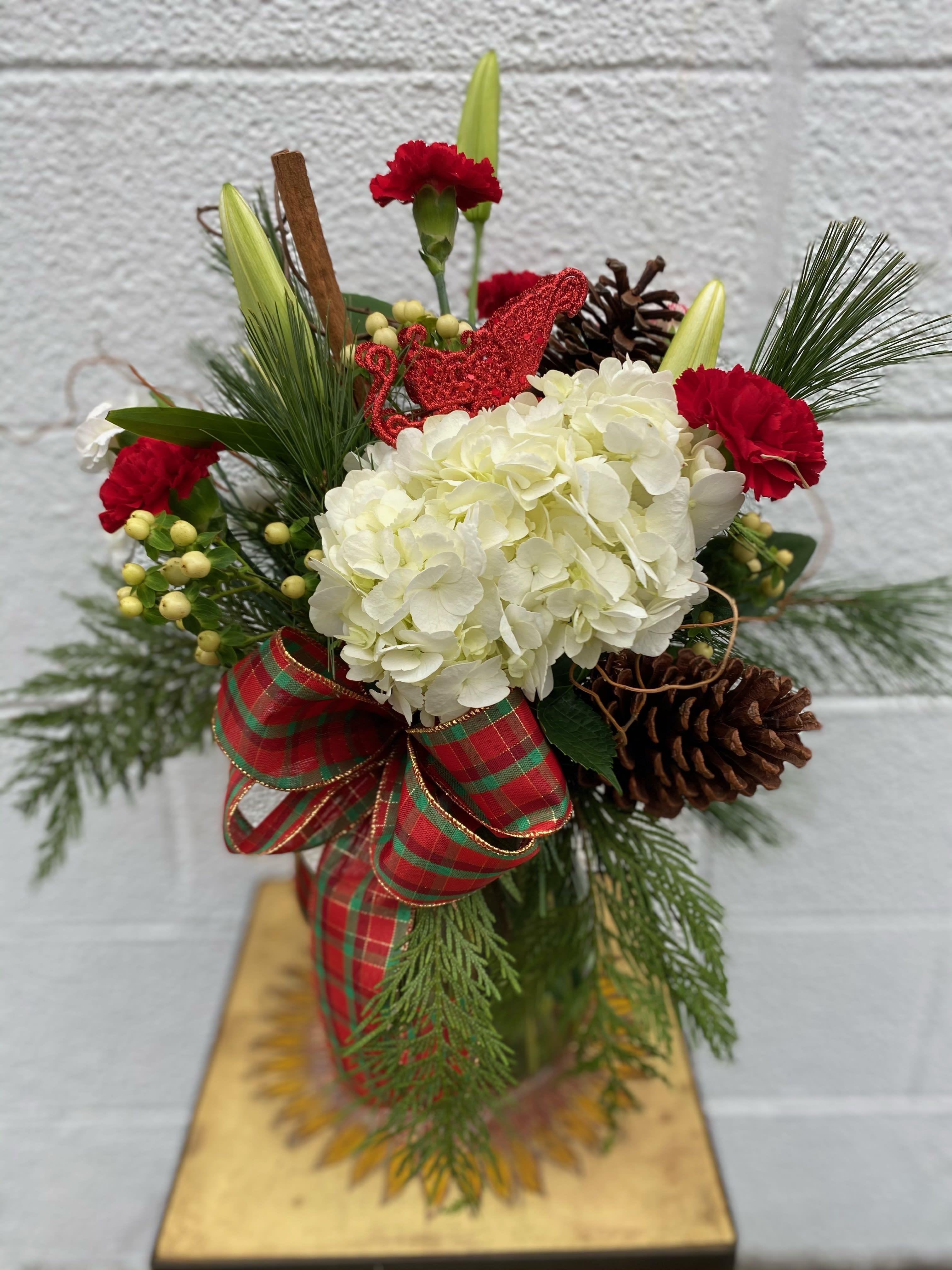 Home for the holidays  - Assorted mixed Christmas evergreens with white and red flowers , includes cinnamon sticks and plaid bow. 