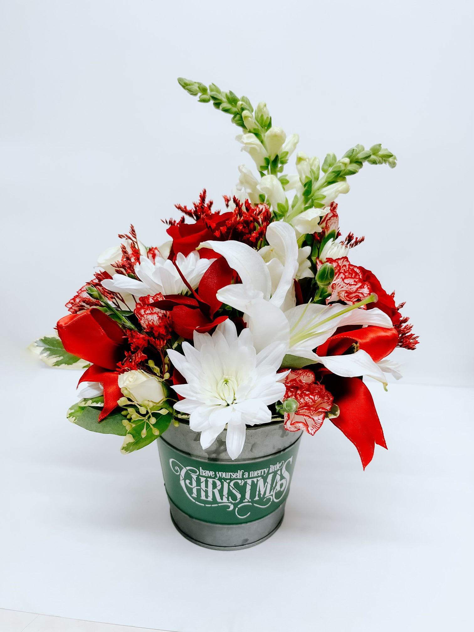 Merry Little Christmas - Give the gift of a Merry Little Christmas in this keepsake tin.  Make a festive statement with this holiday arrangement featuring lilies, snaps and roses.