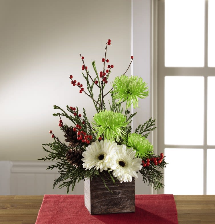 Winter Fun - For the recipient with a refined eye and sophisticated style, this Christmas bouquet becomes that perfect, unforgettable holiday gift. White gerbera daisies capture their attention at the base of this flower arrangement, with stems of green spider chrysanthemums, and red ilex berry stems extending upwards for a unique yuletide look. Accented with an assortment of Christmas greens and presented in a square wooden planter that gives it a natural and warm appearance, this holiday flower bouquet is set to get you noticed as you extend your season's greetings to your friends and family near and far. 