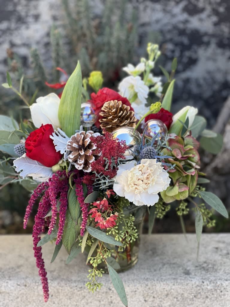 Sweet and Merry - This classic combination of deep red roses and white lisianthus is the perfect holiday combination.  Accents of evergreens and the finishing touch of a bow and pinecone brings the holidays to any lucky recipeient.  