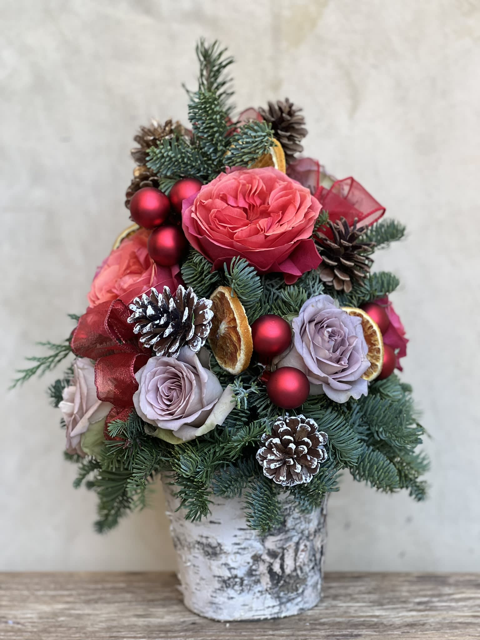Mini Christmas Tree - Fresh tabletop Christmas foliage adorned in real roses, pinecones, ribbon and baubles. This quaint yet elegant arrangement makes for a charming centerpiece or a thoughtful gift. After all good things come in small packages!