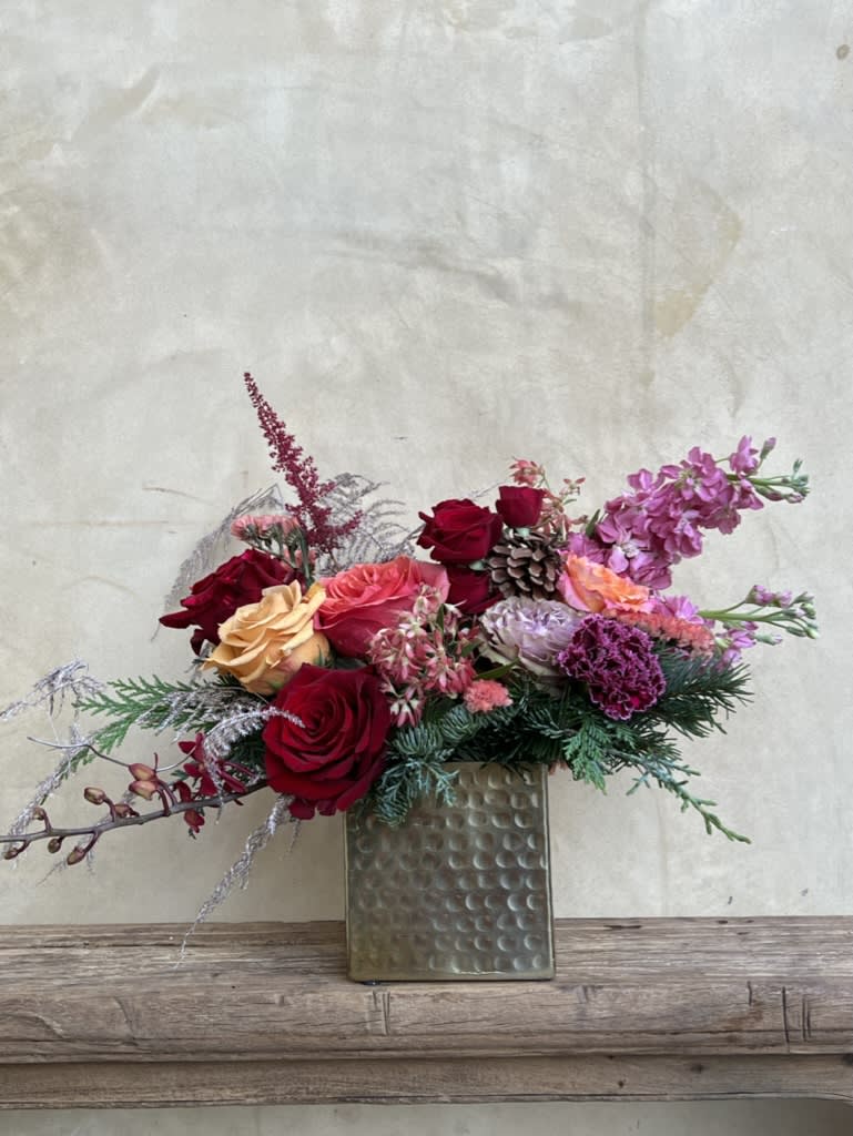 Sugar Cookie  - Sweet and stylish this arrangement is a treat for the eyes, mixing evergreens, roses, and stock in a playful color pallet the evokes warm holiday feelings. 