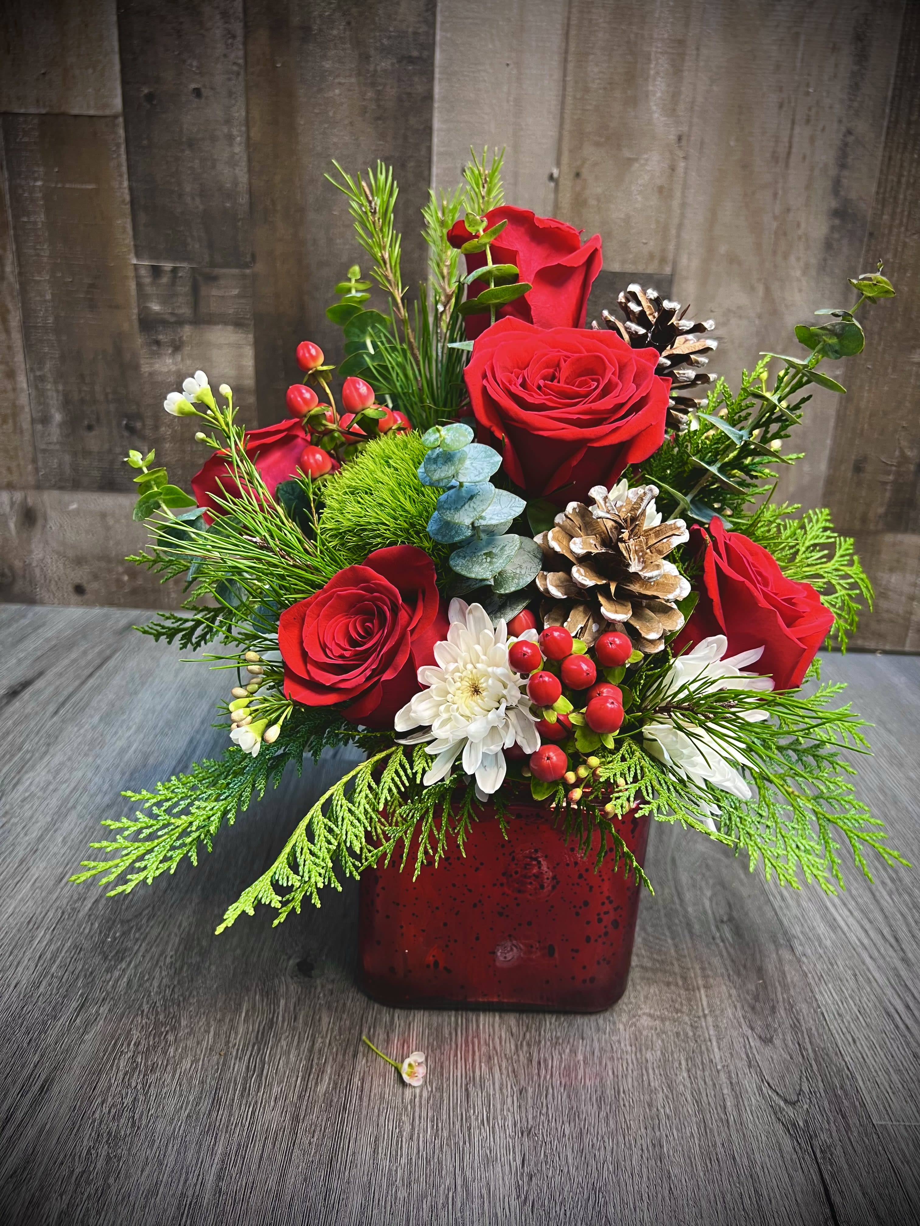 Radiant Reds Christmas -  “Radiant Reds,” a symphony of colors and perfect elegance for the holiday season. This captivating arrangement blends the passion of red roses with the radiant glow of red hypericum visual spectacle that reflects the joy and warmth of Christmas. 14” x 11”