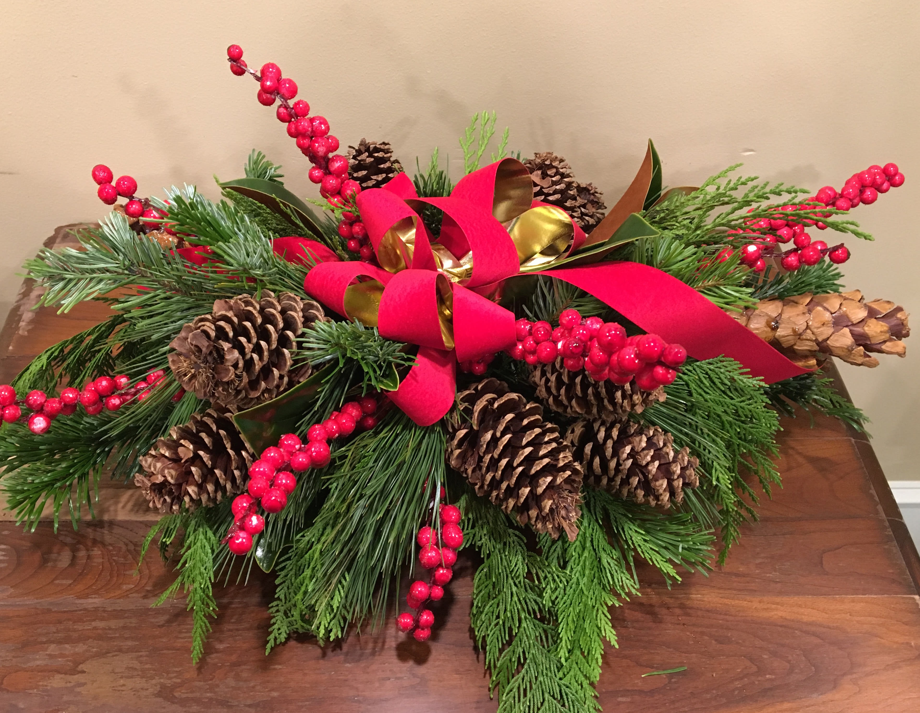 Evergreens forever - Lush evergreens create a beautiful and lasting base accented by pinecones and pretty ribbon, great centerpiece for a coffee table, credenza or dinner table.