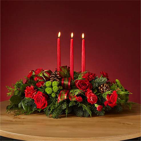 By the Candlelight Centerpiece (BR) - Let time fly By the Candlelight centerpiece as new holiday memories are made. What better way to commemorate the joyful homecoming than with classic red roses and lush evergreen accents? 