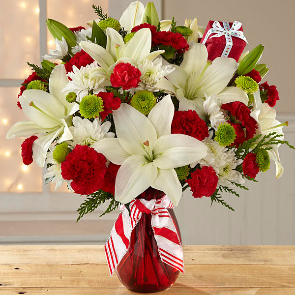  Holiday BOUQUET - Bouquet includes: white Asiatic Lilies, red carnations, red mini carnations, white chrysanthemums, green button poms, and lush holiday greens. Presented with a classic red glass vase and festive ribbon. BETTER bouquet is approximately 19&quot; H X 16&quot; W.