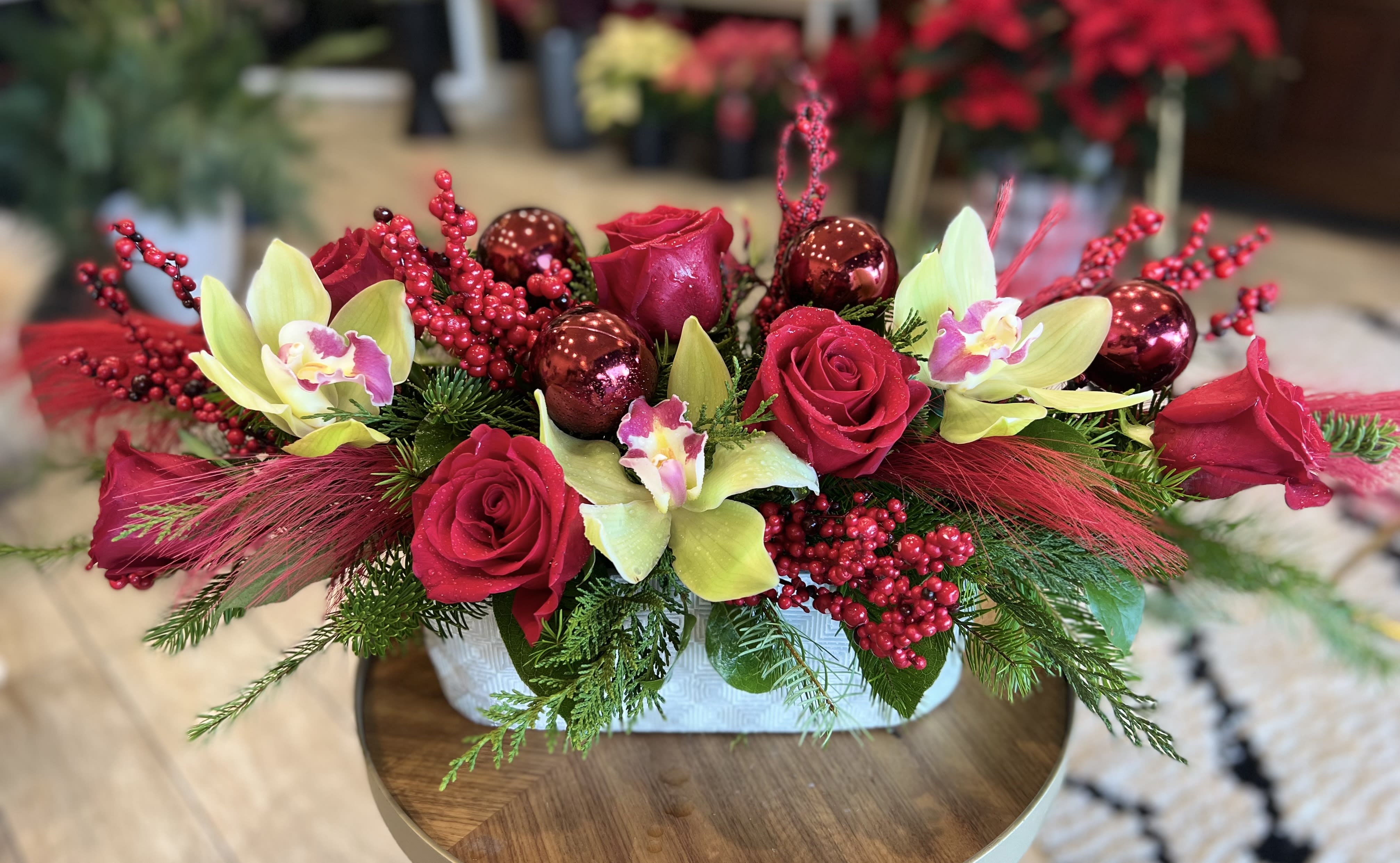 Christmassy  - Stunning centerpiece with red roses and orchids garnished with holiday decor in modern vase 