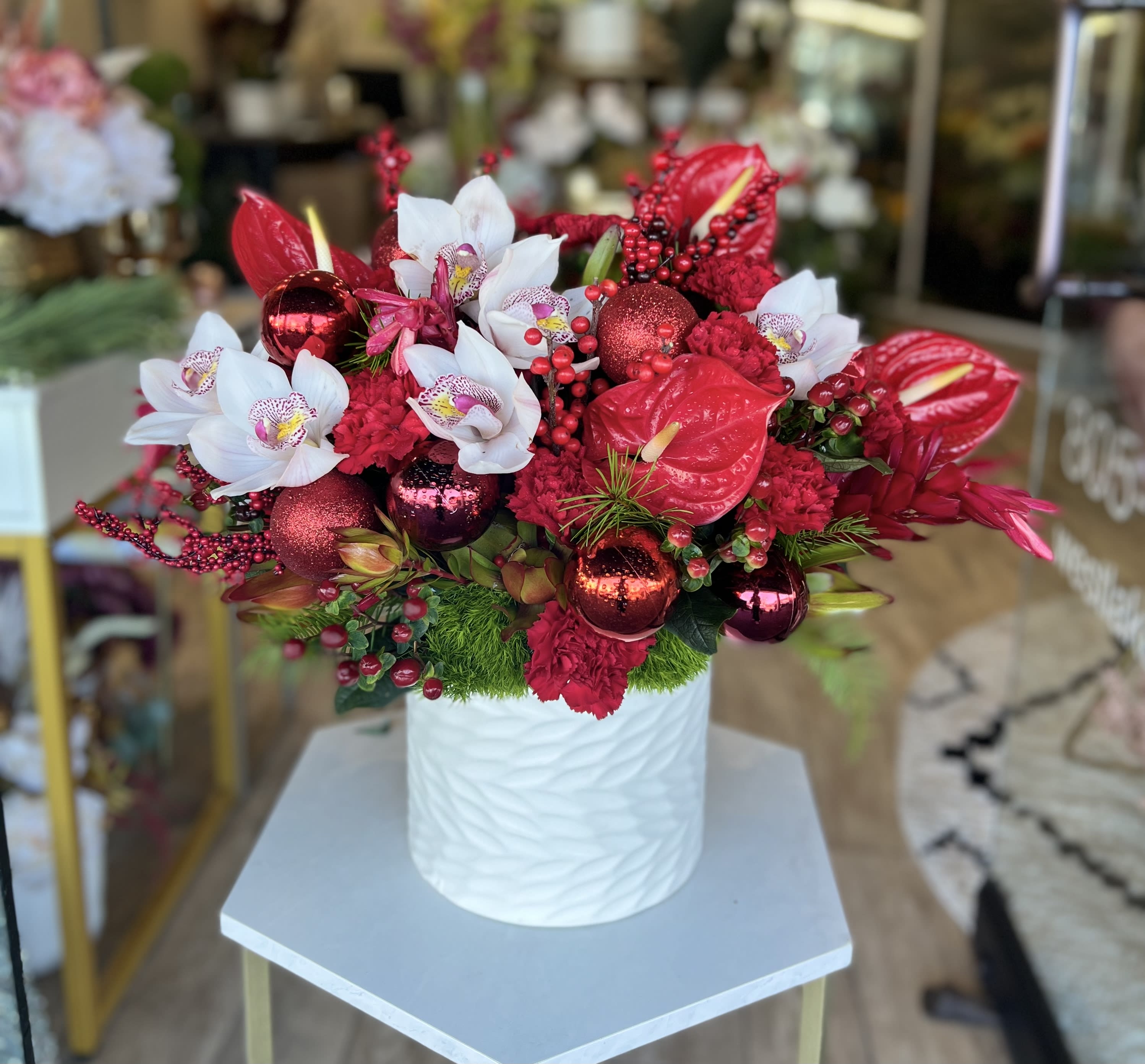 Holiday Jewel - Stunning holiday arrangement with red tropical flowers and garnished with delightful holiday decor 