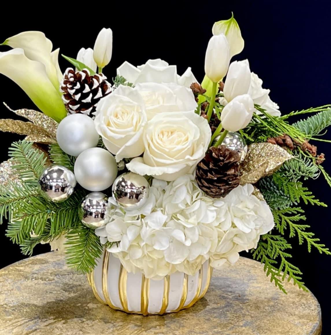 Holiday Blanca  - Beautiful arranged white Roses, Hydrangea, Calla Lillie’s and Tulips,  with Christmas greens in white ceramic container 