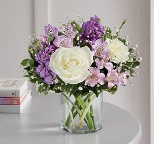 Charming Lavender Bouquet - Meaningful memories begin with thoughtful gestures. Our charming lavender bouquet features a soft, garden-inspired blend of lavender and white blooms, artfully arranged in a clear cylinder vase. Accented with trailing greenery, this hand-designed arrangement is a beautiful way to share what’s in your heart.  Product Details: All-around arrangement with white roses and carnations; lavender Peruvian lilies (alstroemeria) and stock; accented with baby’s breath and assorted greenery Artistically designed a clear glass cylinder vase Extra large arrangement measures approximately 16"H x 12"H Large arrangement measures approximately 15"H x 11"W Medium arrangement measures approximately 13"H x 10"W Small arrangement measures approximately 12"H x 9"W Our florists select the freshest flowers available, so colors, varieties and container may vary due to local availability To ensure lasting beauty, Peruvian lilies may arrive in bud form and will fully bloom over the next few days