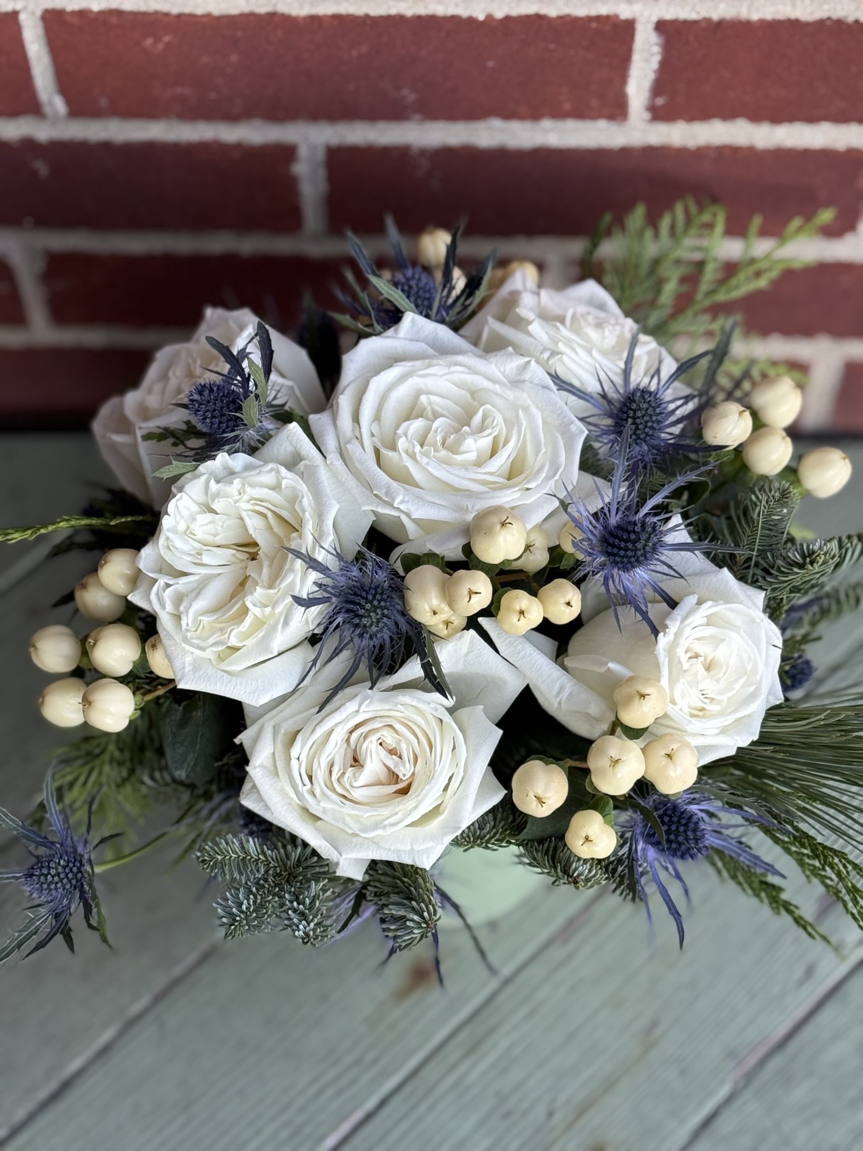 Snow White Sensational Rose bouquet  - We arrange white roses with hypericum and thistle with mixed evergreens. Pot color will vary based on current inventory. 