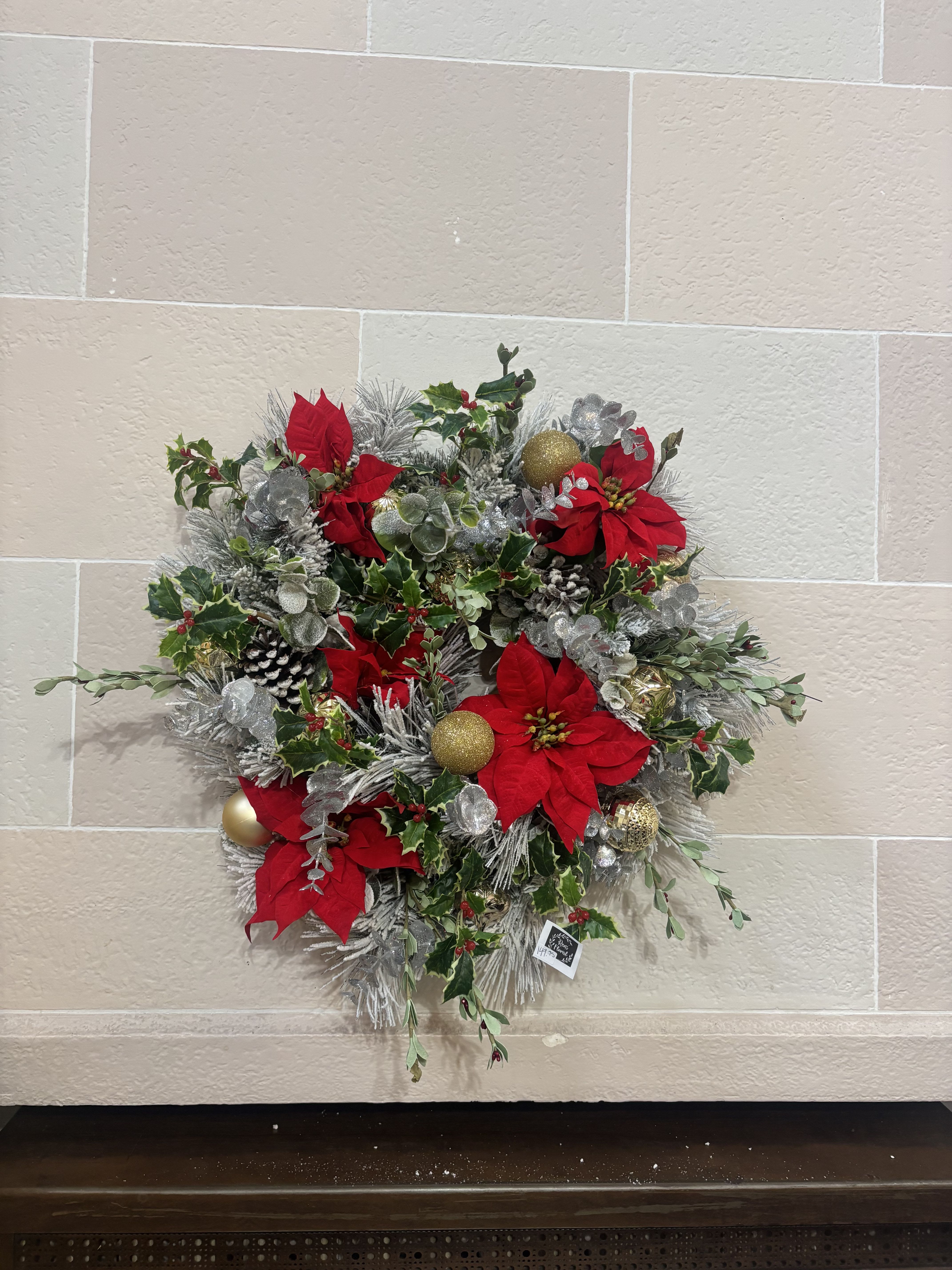 Red and Green Christmas Wreath - A flocked pine wreath with artificial red poinsettias, holly, silver eucalyptus, and gold ornaments. 