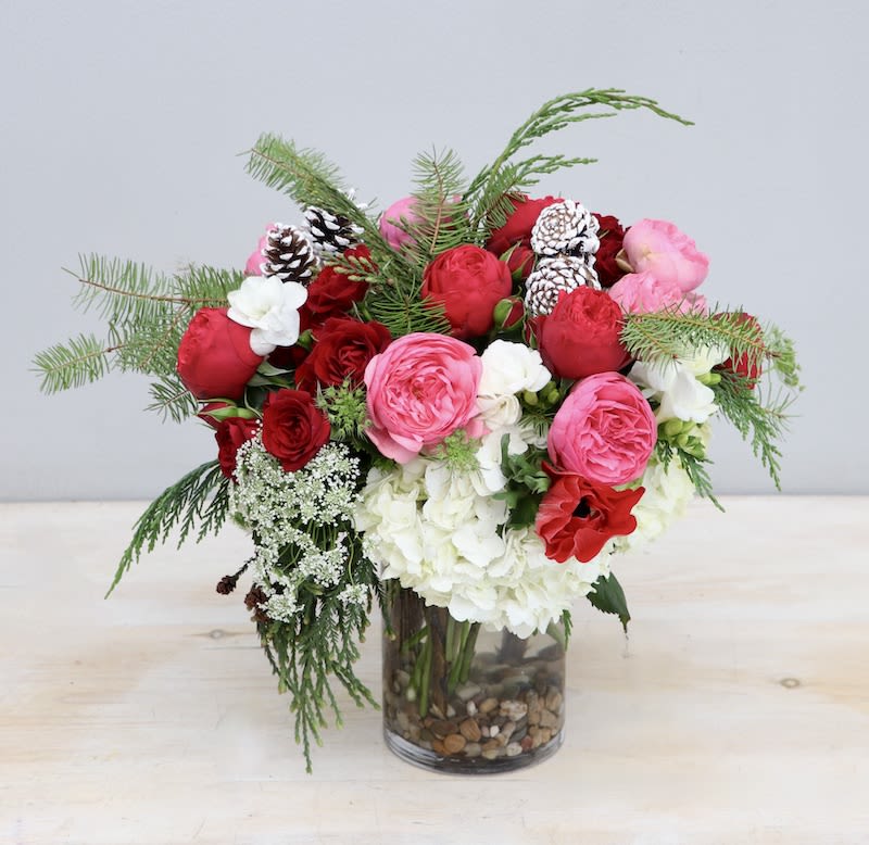 Candy Cane Blooms - WeHo  - Spread the cheer this holiday year with this lovely new arrangement! Mixed with red and pink roses and pine greenery to really give this a holiday feel. Standard size stands at about 10-12 in tall and wide. 