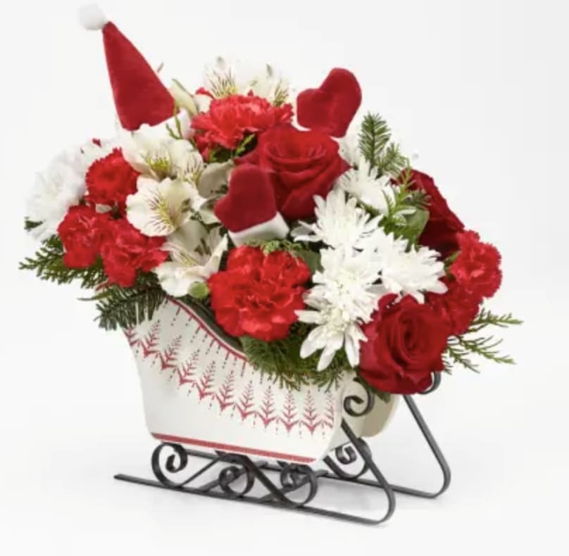 The FTD® Dashing Through the Snow™ Bouquet - Send holiday cheer in the form of a festive holiday arrangement with an assortment of white and red flowers, pine greens all arranged in a hand–painted sleigh. 12"h x 11"w.
