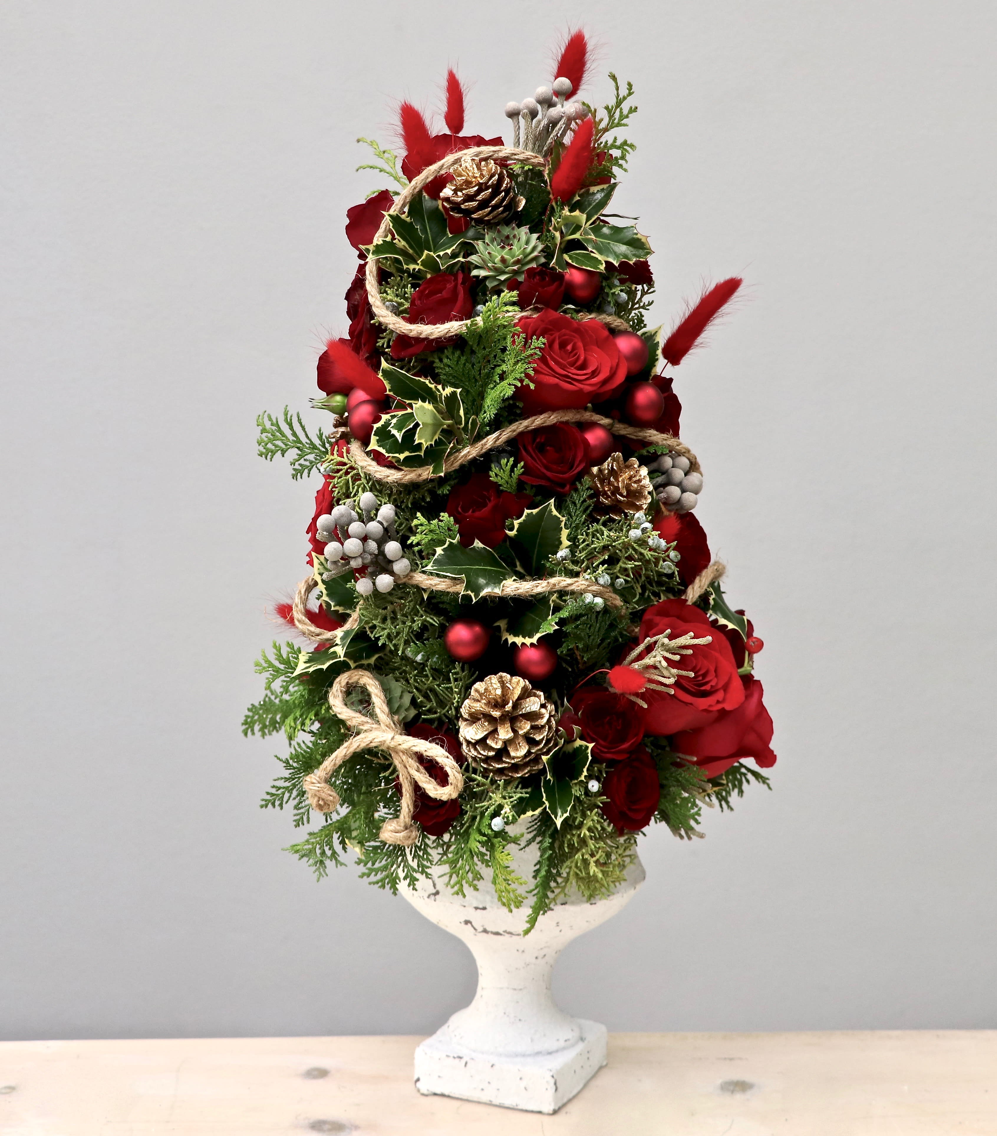 Mini Christmas Tree - Glendale Florist - Festively decked out for the holidays, this beautiful tree stands at approximately 24-26 inches tall in the standard size. Upgrade to premium (like the second photo) for even more blooms and holiday accessories!    