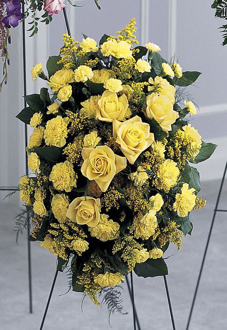 Glowing Tribute Standing Spray - Bright yellow hues catch the eye in this golden standing spray. Yellow roses, carnations, and solidago are arranged with salal and feathery plumosa on an easel. This can also be made in other colors available upon request.