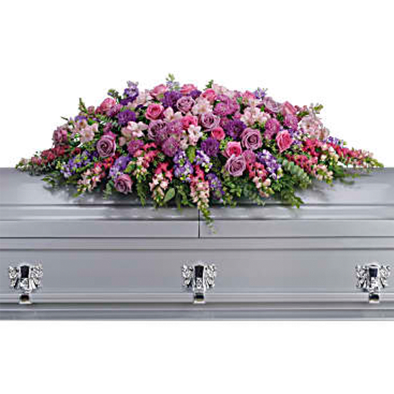 The Lavender Tribute Full Casket Cover - Honor her femininity and generous spirit with a blanket of sweetly scented lavender, pink and purple flowers that create a magnificent final tribute, sincerely expressing devotion and love. Gorgeous flowers such as lavender and pink roses, pink snapdragons and alstroemeria, purple and lavender chrysanthemums. All are entwined with eucalyptus, huckleberry and ming fern.