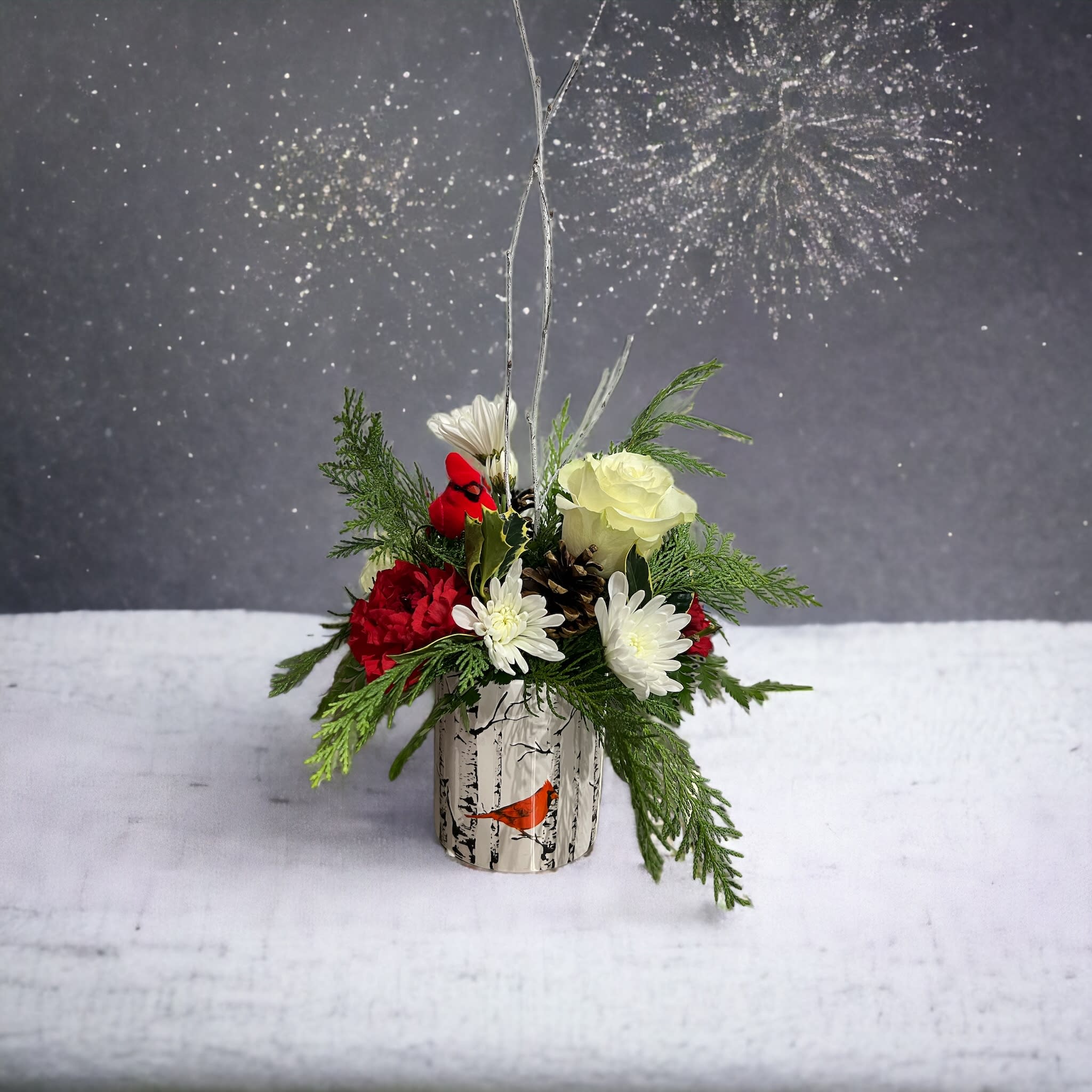 Remembering You - Ceramic container with a  tree and cardinal design filled with assorted evergreens, white roses and red carnations (could be red roses with white carnations), white cushion poms and pine cones 
