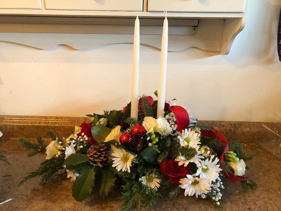 Red and White Centerpiece with candles - A beautiful assortment of red and white flowers such as alstroemeria, roses, daisies, and filler along with holiday greenery and white candles to finish off the display.