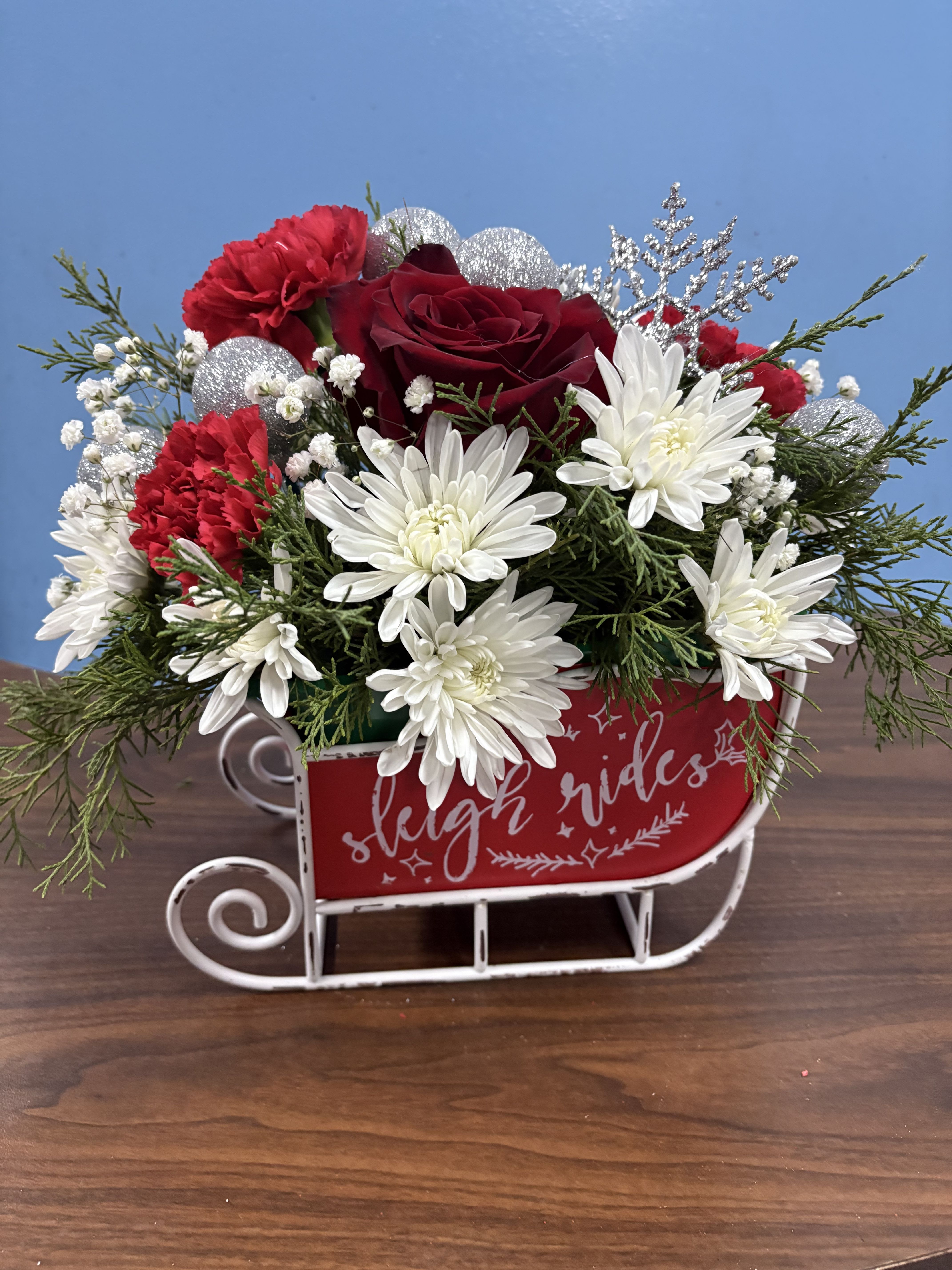 Santa’s Sleigh Ride - Santa’s sleigh decorated in this keepsake sled that your recipient can enjoy for years. Decorated with roses poms, carnations, Christmas greens and Christmas ornaments 