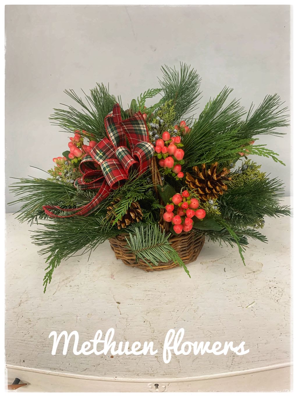 For the holidays basket - basket filled with xmas greens, plaid bow, pine cones and berries