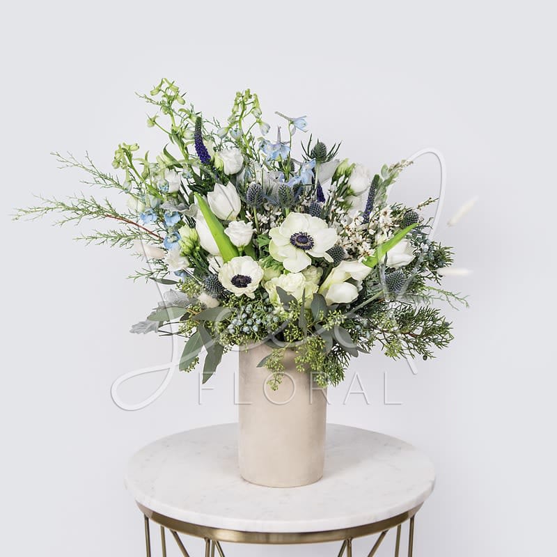 Winter Delight - Featuring: Anemone, Tulip, Thistle, Delphinium, Veronica, Eucalyptus, Dusty Miller, Lisianthus, &amp; Bunny Tails arranged in a Natural Cement Vase