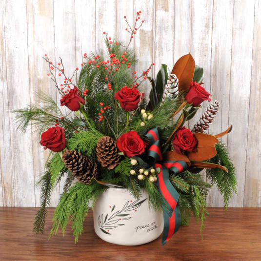 Peace On Earth Large - Large festive mix of red roses, red winterberry, white hypericum berry, magnolia leaves, pinecones and assorted wintergreens in keepsake peace on earth pot.