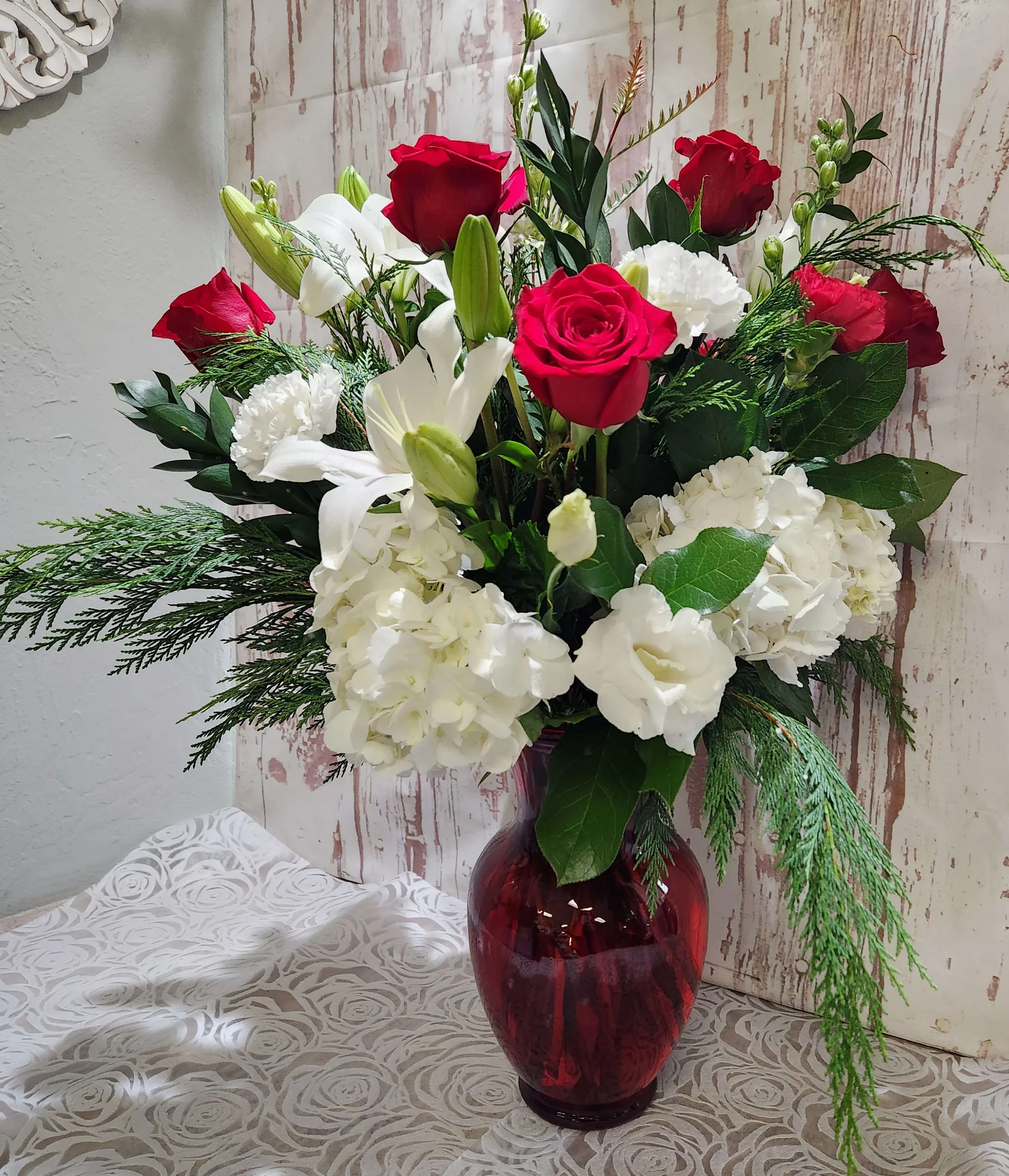 Amour Arrangement  - A beautifully display of classics all mixed together in perfect harmony. Red roses, red and white carnations lush hydrangeas, white lisianthus,  We will use mixed eucalyptus  will be designed in a red or clear garden vase  Standard - will have 5 roses  Deluxe - will have 7 roses Premium will have 10 roses 