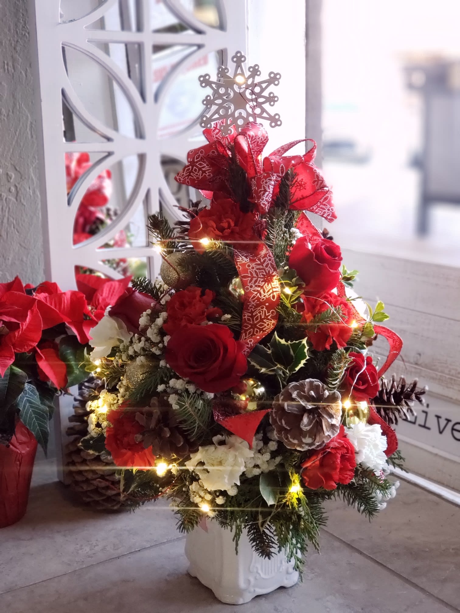 Christmas Trees light up the night - Please order 48 hours ahead  - - Please order 48 hours ahead - A beautiful  mini  Christmas Tree designed with the works Christmas evergreens pinecones, ornaments lights, ribbon and more. Send with love in a white ceramic vase. Tree may vary in ornament's and ribbons.  