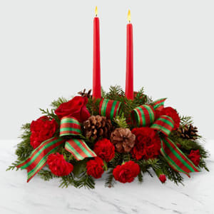 Holiday Plaid Candle Arrangement  - Drawing from the rich traditions of holiday décor, this festive centerpiece is set to lend its seasonal beauty to your holiday celebrations. Bright red roses, carnations and mini carnations are arranged amongst an assortment of holiday greens, accented with natural pinecones and a designer red and green striped ribbon. Two red taper candles, this lovely centerpiece will bring warmth and Christmas charm to your holiday gatherings with each graceful bloom. 