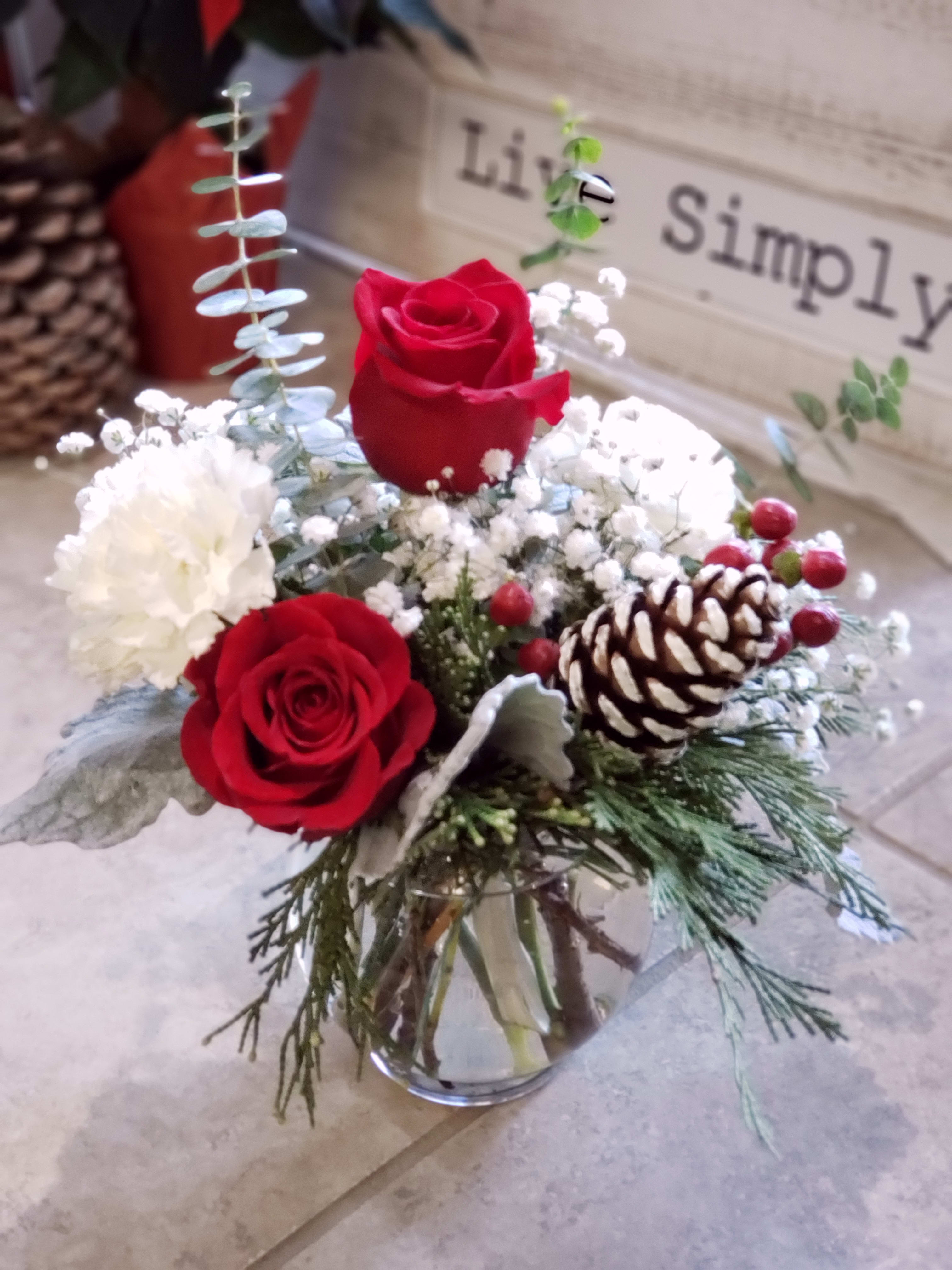 Mini Christmas Mix bubble bowl   - A cute Christmas mix designed in a clear bubble bowl or clear cylinder full of winter evergreens pine cones red roses,  white carnations, eucalyptus, dusty miller and snow white babies breath.  A sweet way to say I am thinking of you, I love you. just because or a simple thank you arrangement. This sweet arrangement will sit beautiful on a small coffee table or in a small work space.     