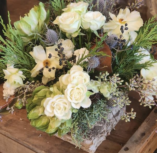 Enchanted Forest - A perfect addition to anyone's holiday gathering. Our Enchanted Forest centerpiece is filled with lush and seasonal evergreens and eucalyptus. Hints of soft yellow, white and blue flowers that give this nature inspired beauty its unique appearance and natural look.  Houses in a wood or clear glass vase  Every effort will be made to recreate your chosen design. Please note that from time to time due to product availability and quality we may need to make substitutions. We will make sure to keep the original design in mind when making substitutions. 