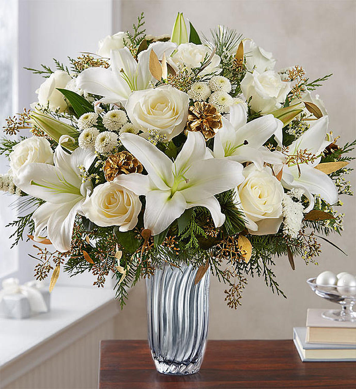 Winter Radiance - Share winter’s undeniable radiance with one unforgettable gift. Our luxurious new arrangement flaunts an abundance of all-white blooms, evergreens and glistening gold accents. 