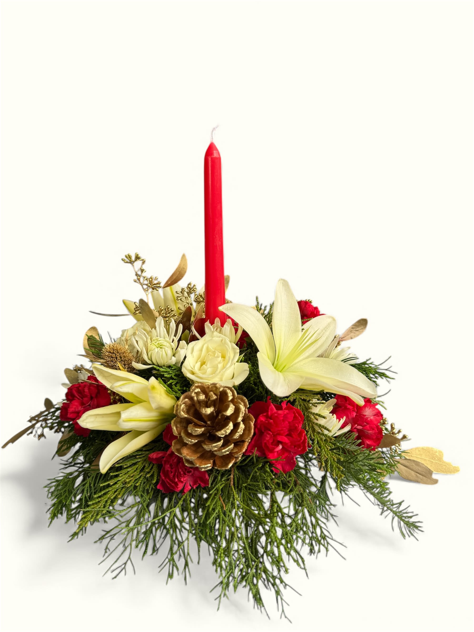 Christmas Classic Centerpiece - Bring classic holiday charm to your table with this festive Christmas Classic centerpiece. Featuring elegant white lilies, creamy roses, vibrant red carnations, fresh winter greenery, and a shimmering gold pinecone, it’s finished with a traditional red taper candle for a warm seasonal glow. Perfect for holiday dinners, gifting, or adding a touch of Christmas magic to any room.