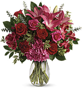Love Struck Bouquet - A luxurious bouquet that's sure to leave your special someone absolutely love struck! There's no denying the dramatic beauty of these radiant, red hot roses, hydrangea and lilies. This luxe arrangement includes pink hydrangea, hot pink roses, red roses, dark pink asiatic lilies, dark pink alstroemeria, maroon carnations, pitta negra, spiral eucalyptus, and lemon leaf. Delivered in a glass  vase. Approximately 17&quot; W x 18&quot; H